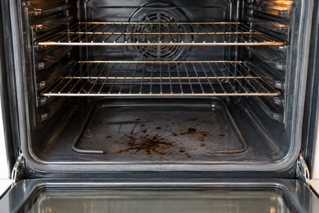 Baked-on food and grease residue on the bottom of a cooled oven